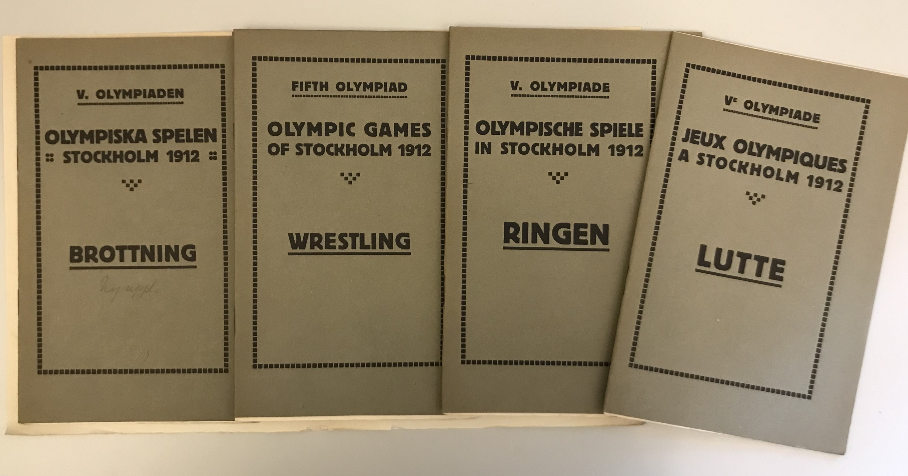 Färgfotografi av omslagen på fyra grågröna broschyrer med svart text på svenska, engelska, tyska och franska.