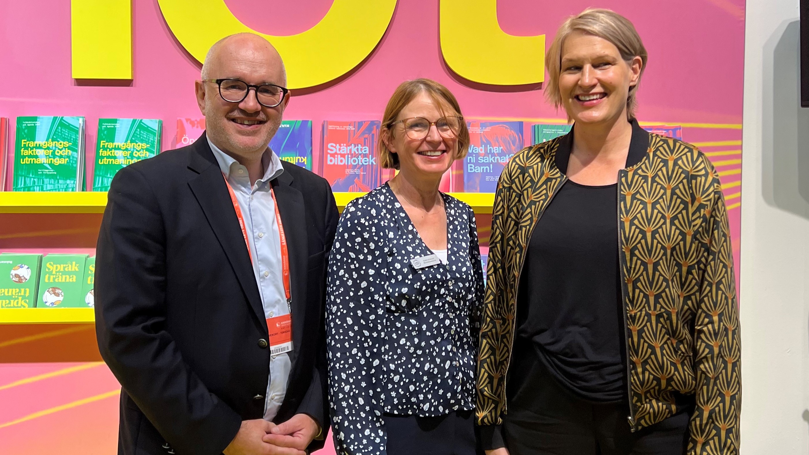 Tre personer, Magnus Larsson (MTM), Karin Grönvall (KB) och Kajsa Ravin (Kulturrådet) ler mot kameran med en bokvägg i bakgrunden.